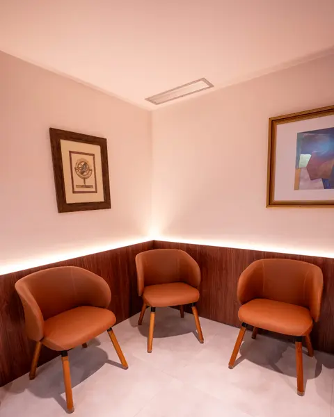 Sala de espera com poltronas em tom terracota e quadros na parede